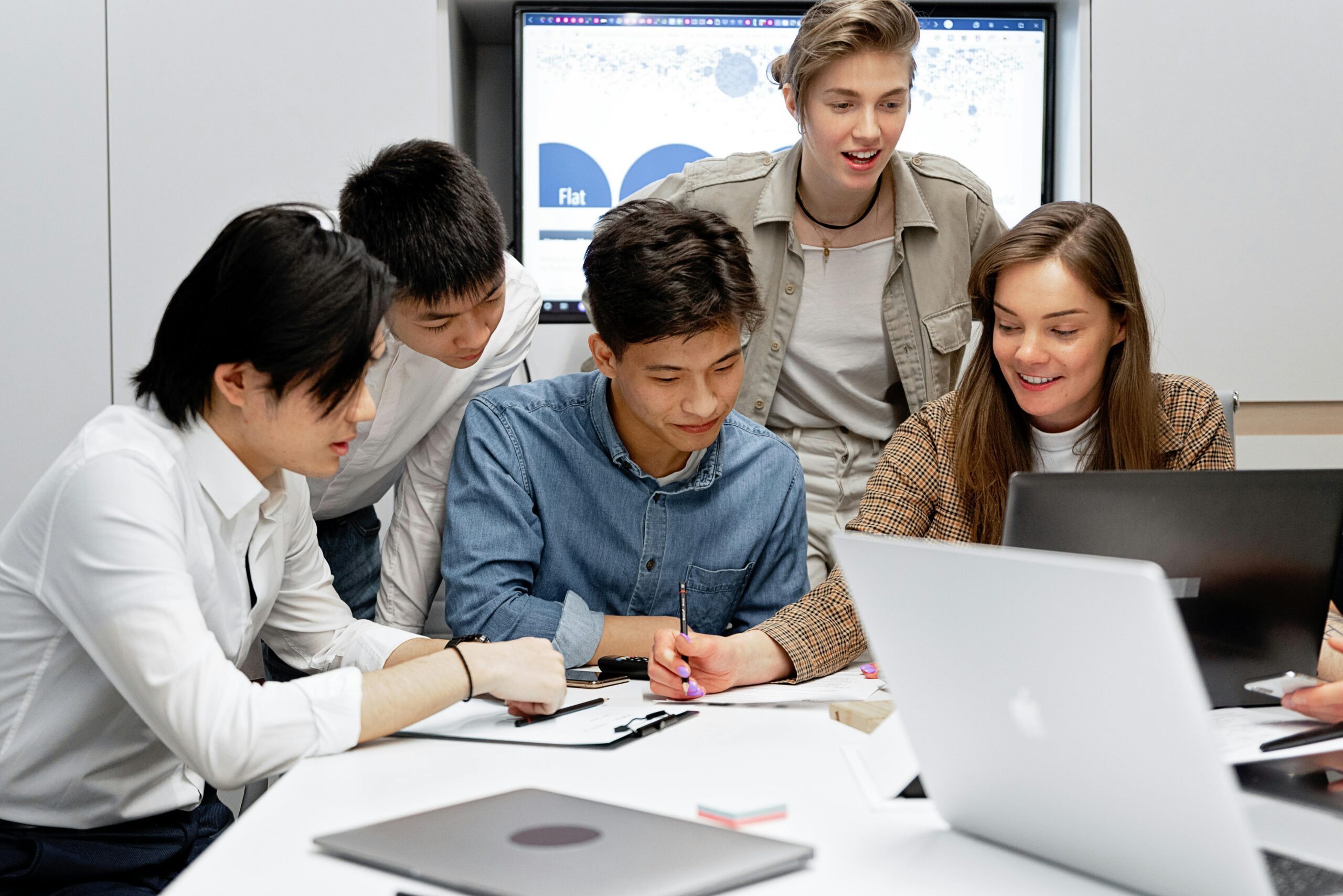 Young professionals brainstorming together with laptops in a bright, modern office.